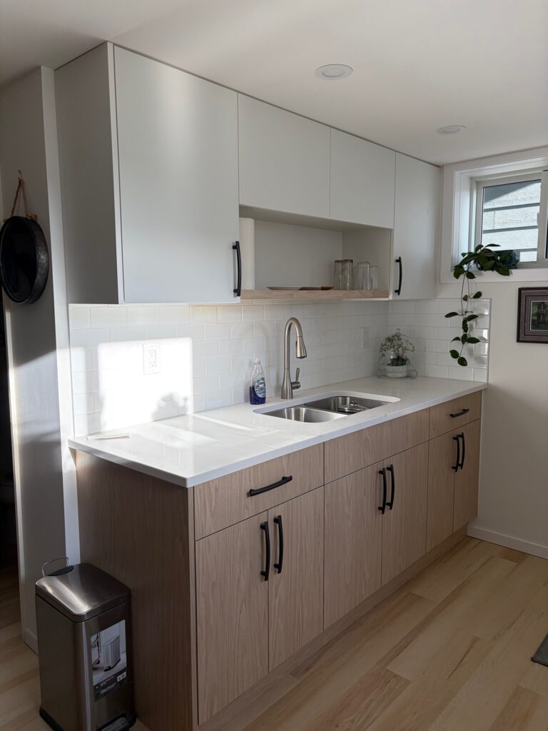 White upper cabinets and an open woodgrain shelf above the sink, with matching woodgrain lower cabinets