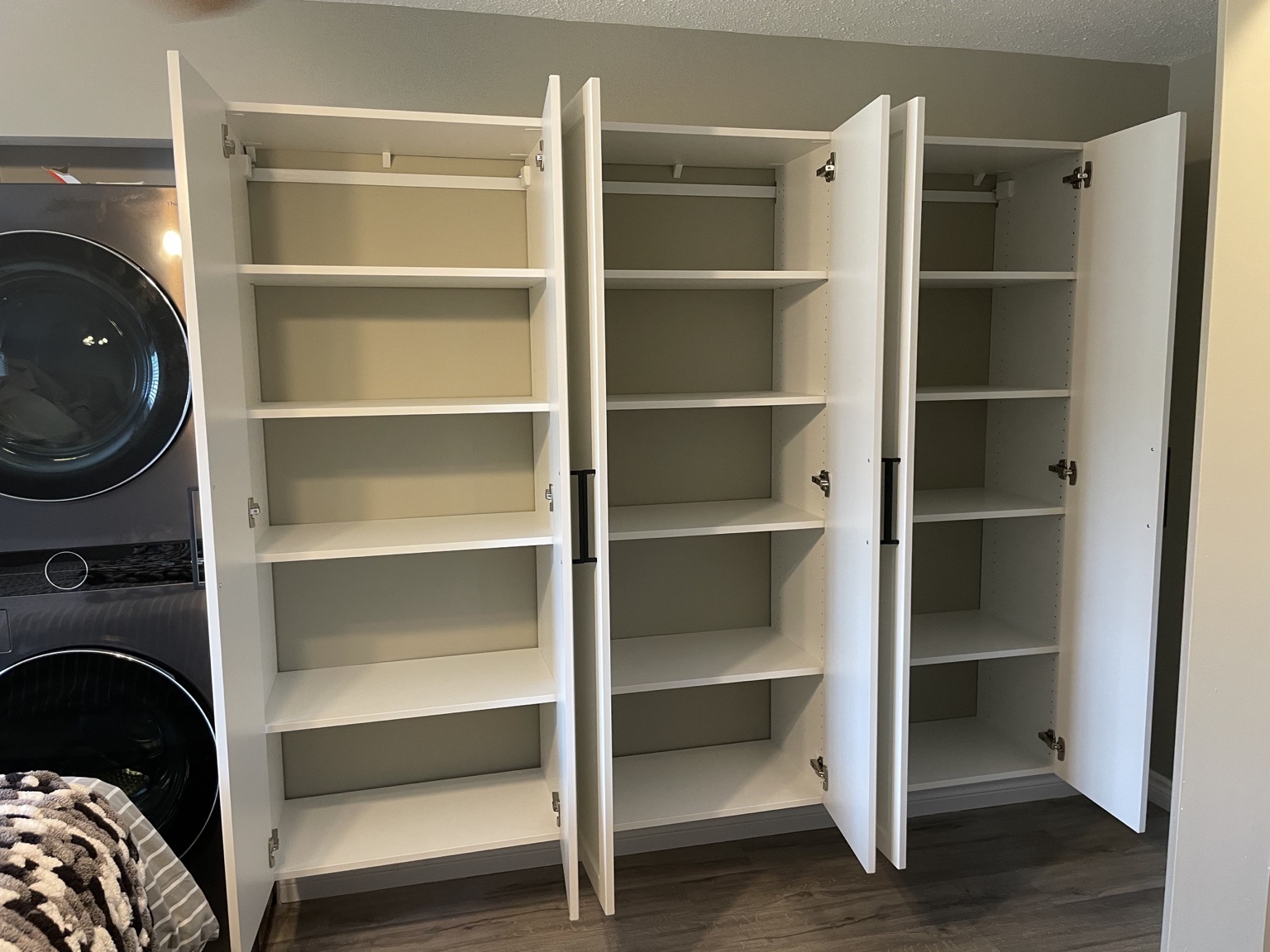 White storage cabinets with doors open, showing three sections of adjustable shelving